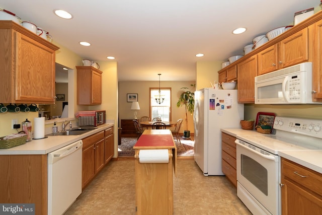 kitchen with a center island, pendant lighting, white appliances, and sink