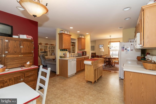 kitchen with white appliances, a center island, hanging light fixtures, and sink