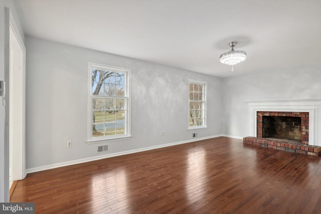 unfurnished living room with dark wood-type flooring and a brick fireplace