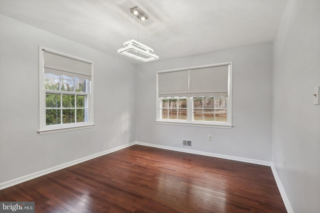 unfurnished room featuring a notable chandelier and dark hardwood / wood-style floors