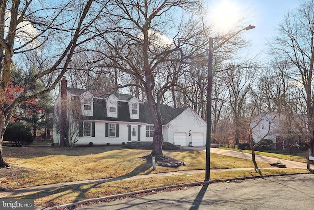 cape cod home featuring a garage and a front lawn