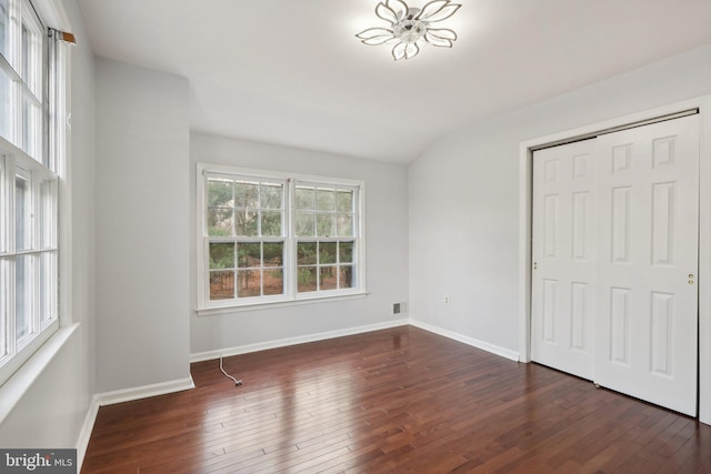 unfurnished bedroom with a closet, dark hardwood / wood-style flooring, and vaulted ceiling