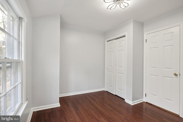 unfurnished bedroom with dark wood-type flooring and a closet