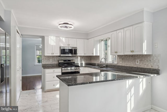 kitchen with white cabinets, sink, dark stone countertops, appliances with stainless steel finishes, and kitchen peninsula