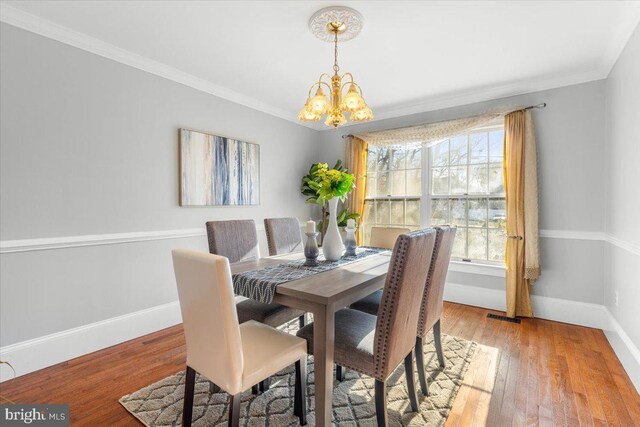 dining room featuring crown molding, light hardwood / wood-style floors, and an inviting chandelier