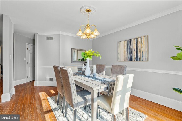 dining space featuring ornamental molding, a notable chandelier, and hardwood / wood-style flooring