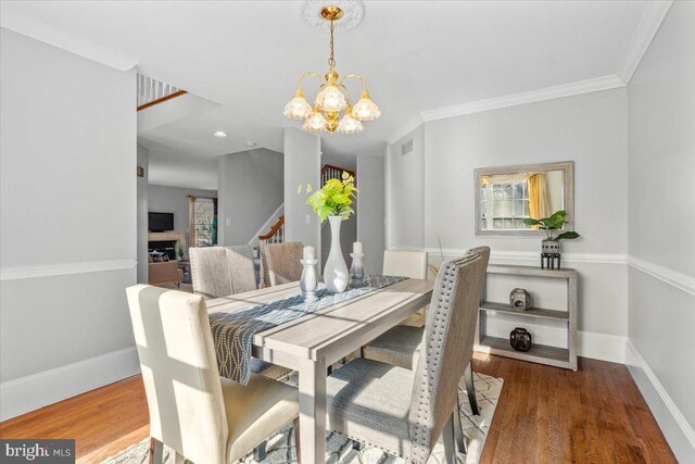 dining space with ornamental molding, an inviting chandelier, and dark wood-type flooring