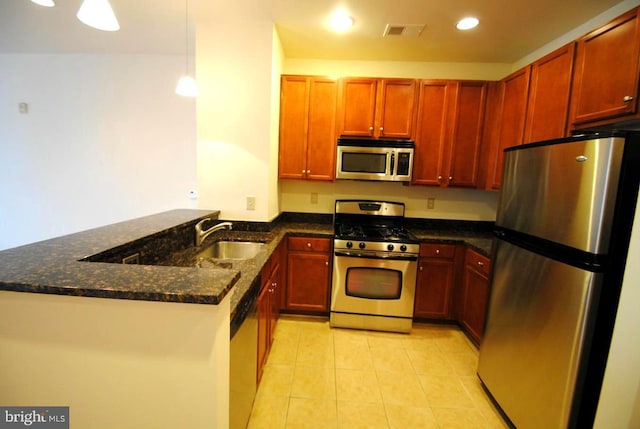 kitchen featuring sink, hanging light fixtures, stainless steel appliances, kitchen peninsula, and dark stone counters