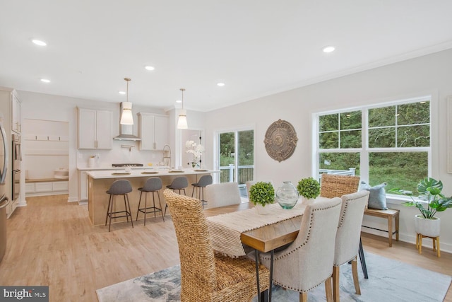 dining area with light hardwood / wood-style floors, ornamental molding, and sink