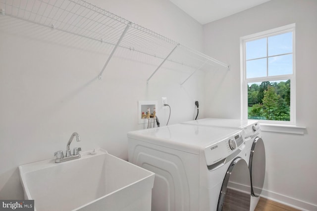 clothes washing area featuring wood-type flooring, separate washer and dryer, and sink