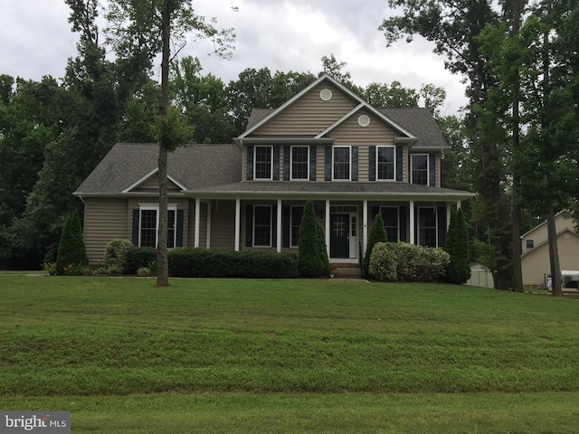 colonial house with covered porch, a front yard, and a storage unit