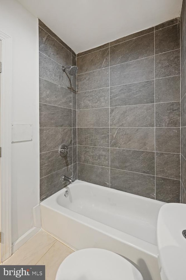 bathroom featuring tile patterned flooring, tiled shower / bath combo, and toilet