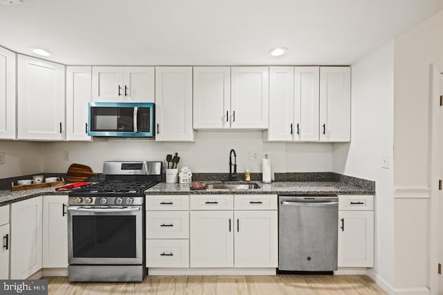 kitchen with dark stone countertops, sink, white cabinets, and stainless steel appliances