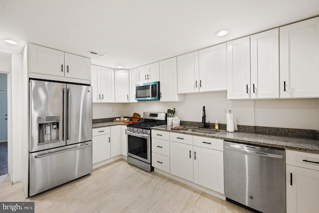 kitchen with dark stone countertops, sink, white cabinets, and stainless steel appliances