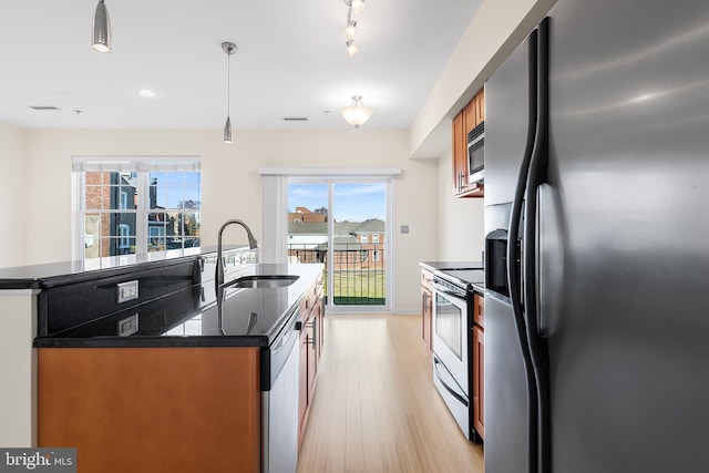 kitchen with hanging light fixtures, stainless steel appliances, plenty of natural light, and sink