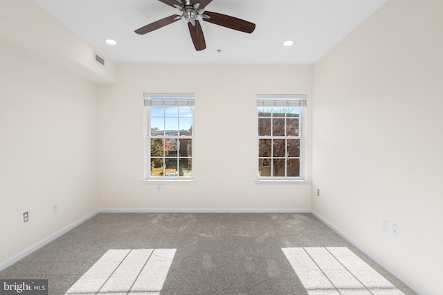 carpeted spare room featuring plenty of natural light and ceiling fan