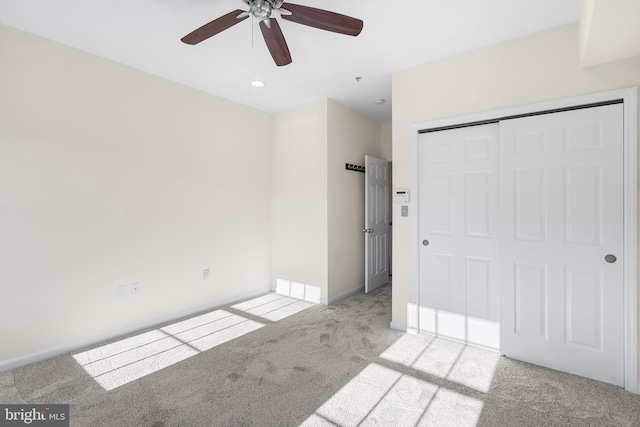 unfurnished bedroom featuring ceiling fan, light colored carpet, and a closet