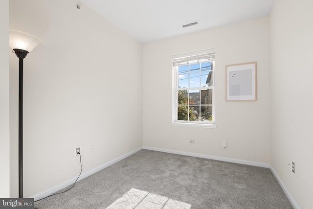 unfurnished room with carpet floors, visible vents, and baseboards