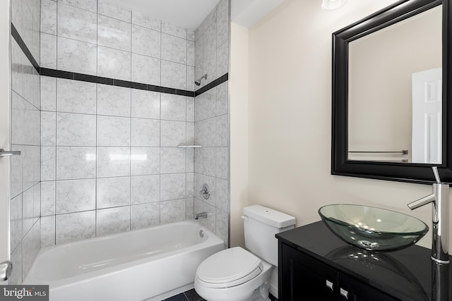 full bathroom featuring vanity, tiled shower / bath combo, and toilet