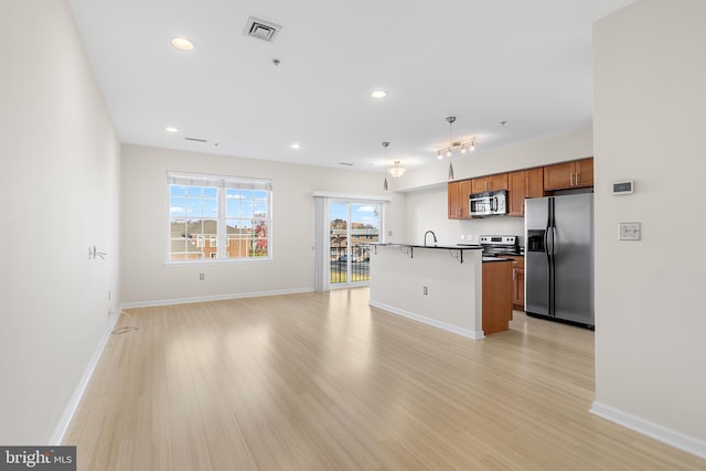 kitchen featuring a kitchen island with sink, sink, a breakfast bar area, light hardwood / wood-style floors, and stainless steel appliances