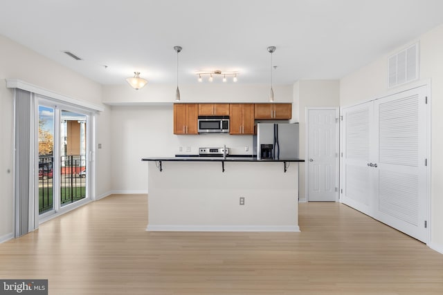 kitchen featuring a breakfast bar area, light hardwood / wood-style flooring, stainless steel appliances, and decorative light fixtures