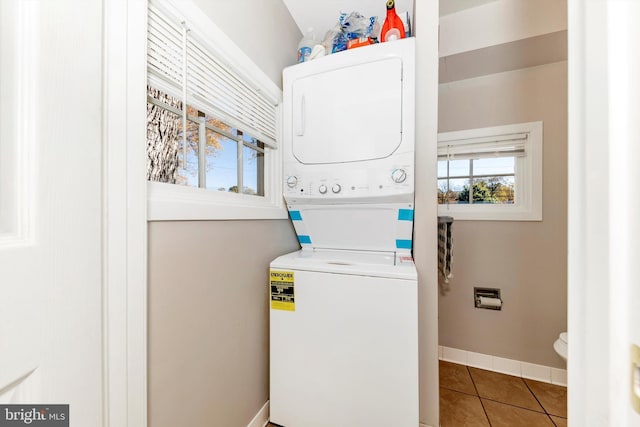 clothes washing area with tile patterned floors and stacked washer and dryer