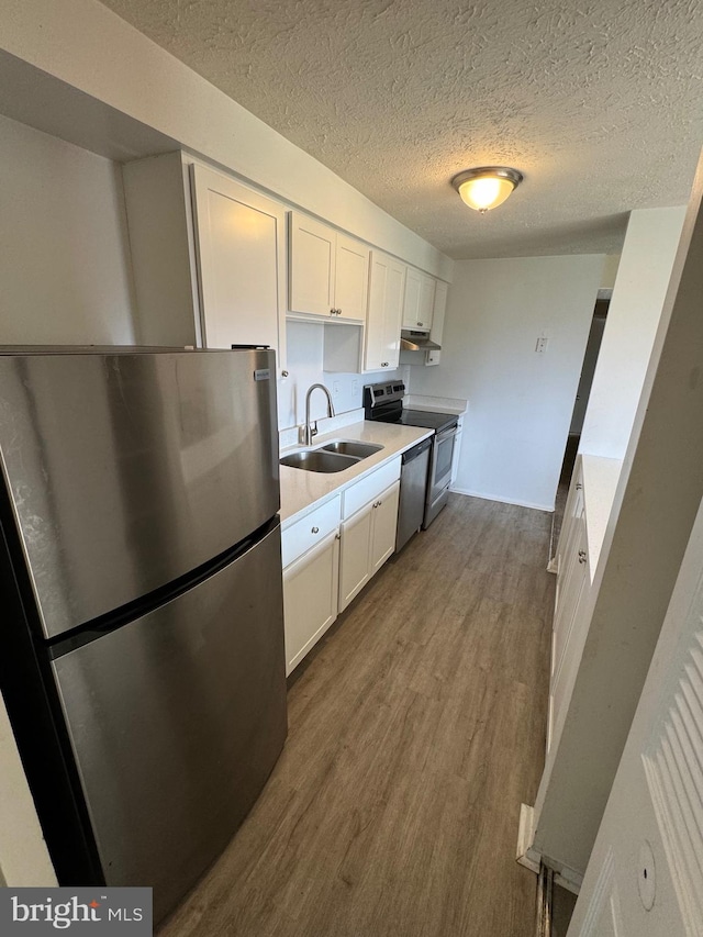 kitchen with hardwood / wood-style floors, sink, a textured ceiling, white cabinetry, and stainless steel appliances