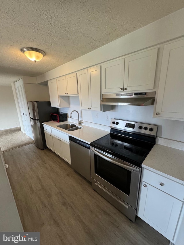 kitchen featuring white cabinetry, sink, dark wood-type flooring, stainless steel appliances, and a textured ceiling