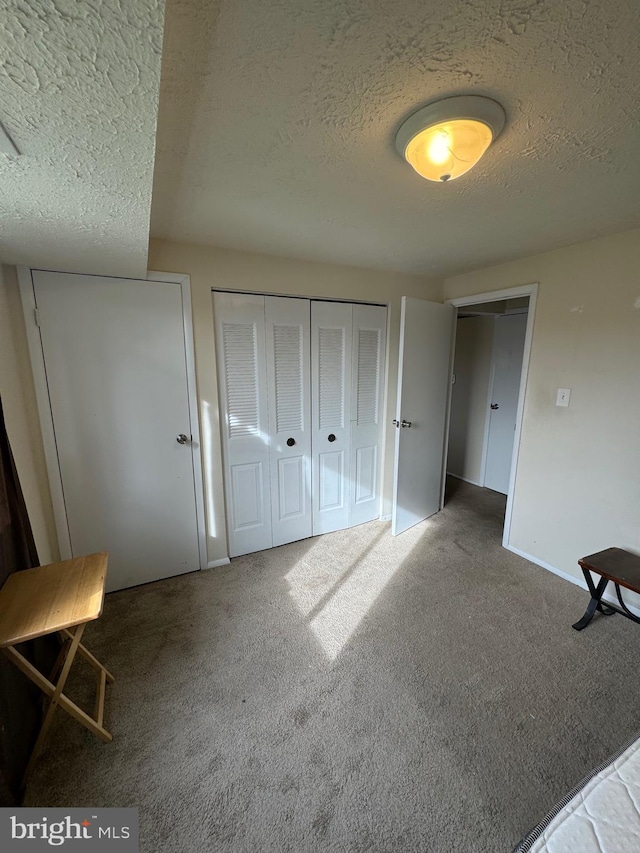 unfurnished bedroom featuring carpet, a textured ceiling, and a closet