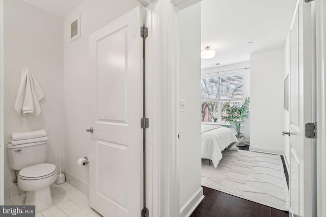 bathroom featuring wood finished floors, visible vents, baseboards, toilet, and connected bathroom