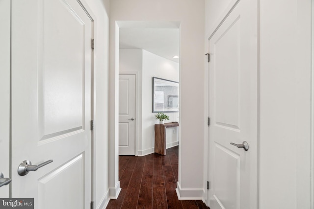 hallway featuring dark wood-type flooring and baseboards