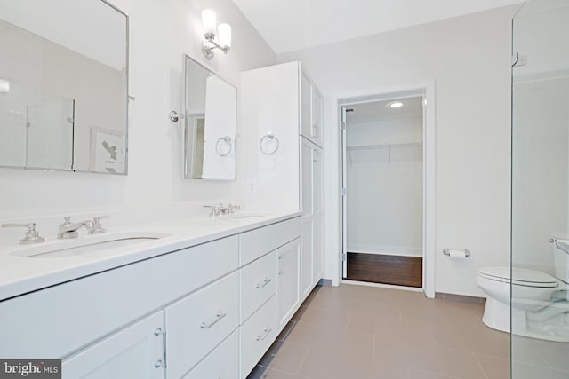 full bathroom featuring double vanity, tile patterned floors, toilet, and a sink