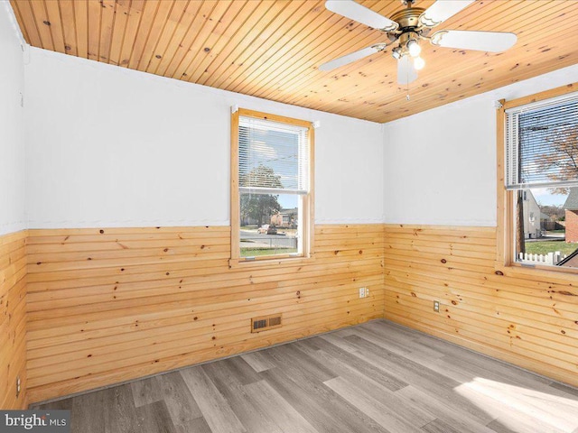 spare room with wood walls, ceiling fan, light hardwood / wood-style floors, and wooden ceiling