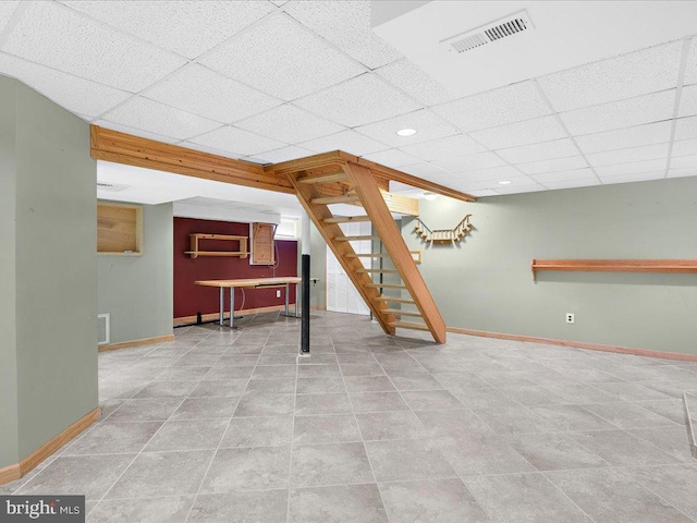 basement with a paneled ceiling and light tile patterned floors