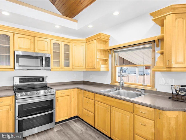 kitchen with sink, stainless steel appliances, wood-type flooring, vaulted ceiling, and light brown cabinetry