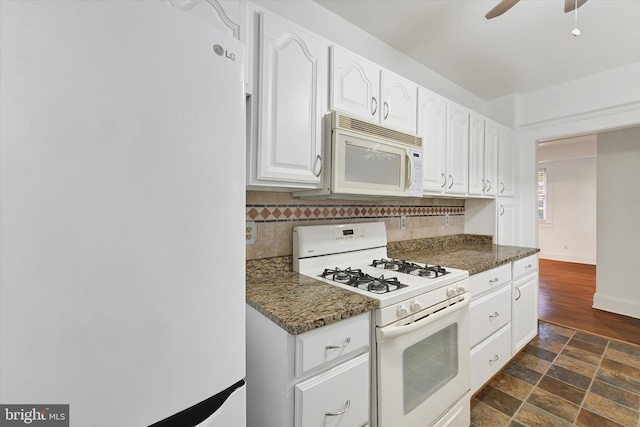 kitchen with decorative backsplash, white cabinets, dark stone counters, and white appliances