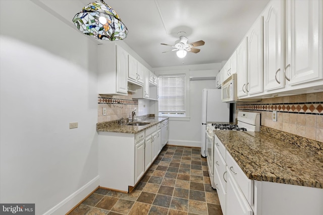 kitchen with decorative backsplash, dark stone counters, white appliances, ceiling fan, and white cabinets