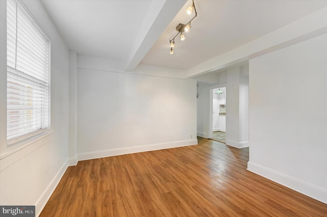 empty room with beamed ceiling and hardwood / wood-style flooring