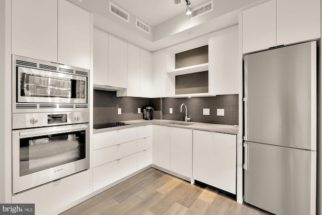 kitchen featuring sink, white cabinets, light hardwood / wood-style floors, and appliances with stainless steel finishes