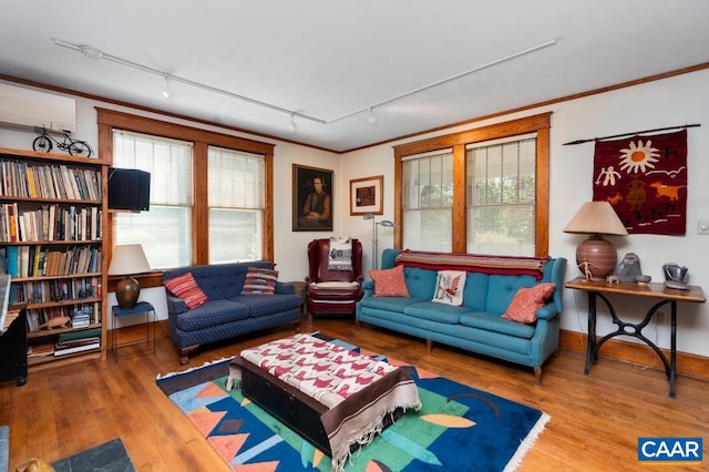 living room featuring hardwood / wood-style flooring, ornamental molding, rail lighting, and a wall unit AC