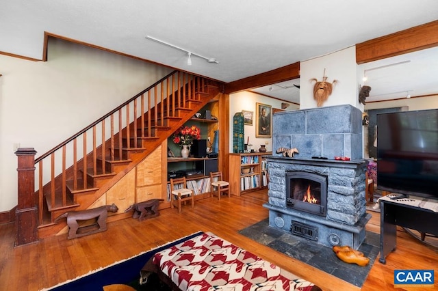 living room featuring a stone fireplace, hardwood / wood-style floors, and rail lighting