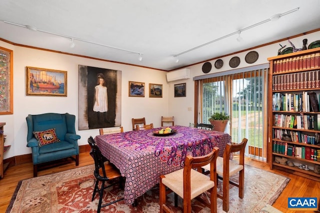 dining space featuring hardwood / wood-style floors, track lighting, and a wall mounted AC