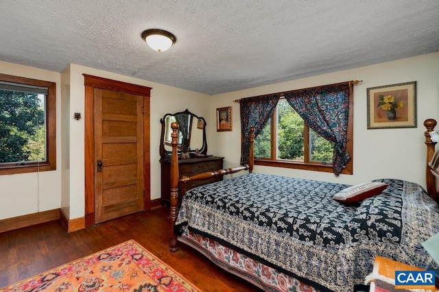 bedroom featuring multiple windows, dark wood-type flooring, and a textured ceiling