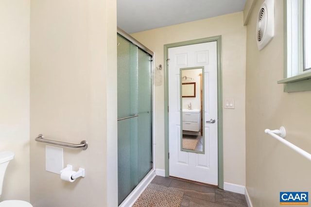 bathroom with tile patterned floors, toilet, a shower with shower door, and sink