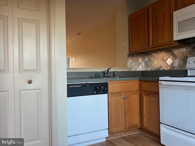 kitchen with tasteful backsplash, white appliances, sink, hardwood / wood-style floors, and lofted ceiling