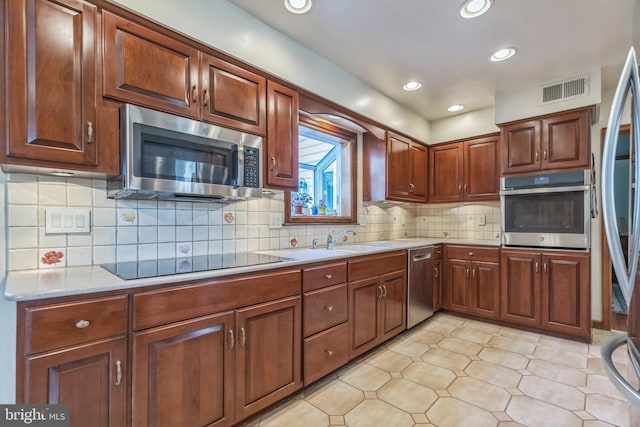 kitchen featuring tasteful backsplash, sink, light tile patterned floors, and appliances with stainless steel finishes