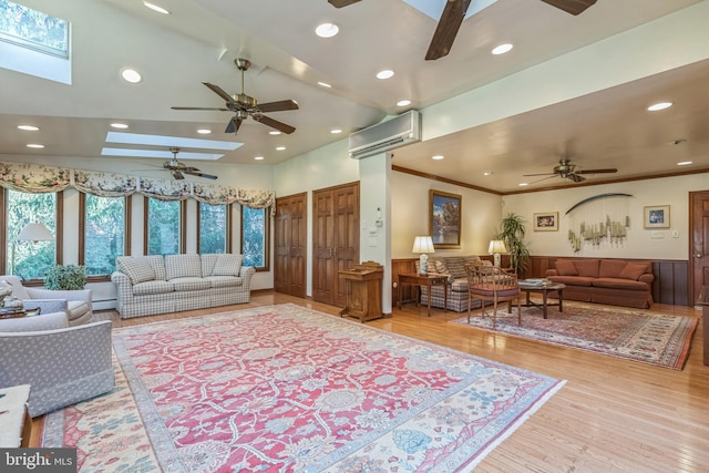 living room with ceiling fan, light wood-type flooring, an AC wall unit, and a skylight