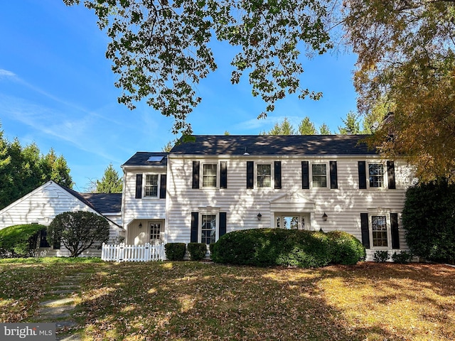 colonial-style house featuring a front lawn