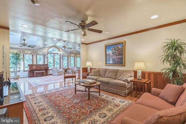 living room featuring a baseboard heating unit, light hardwood / wood-style flooring, ceiling fan, and ornamental molding