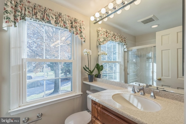 bathroom featuring a shower with door, vanity, and toilet